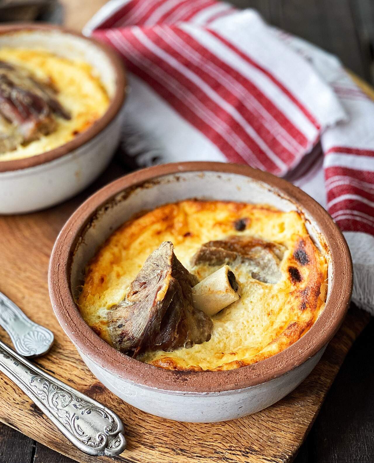 A golden-baked tavë kosi with lamb in a traditional clay dish — Albania's national dish