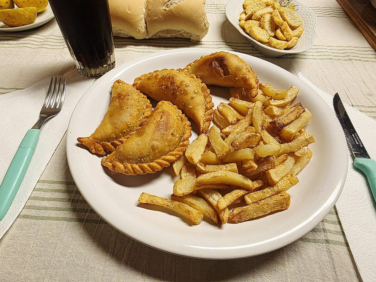 Golden fried Argentine beef empanadas with crimped edges, served with homemade French fries