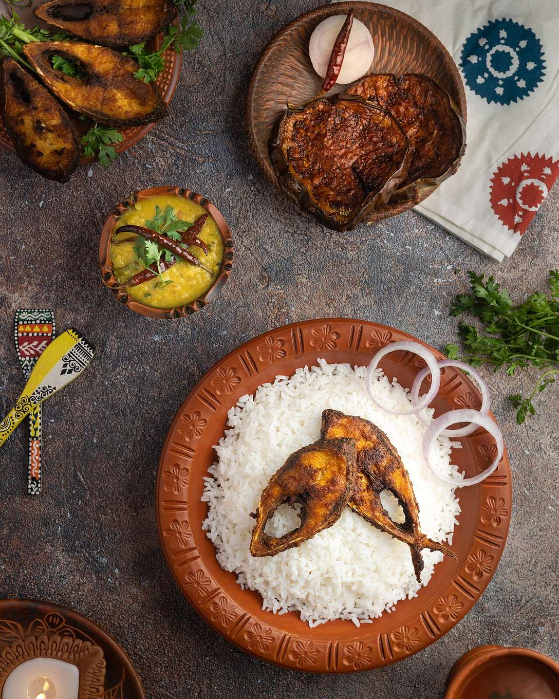 Fried hilsa (ilish) served over rice with eggplant fry and dal — a traditional Bangladeshi spread
