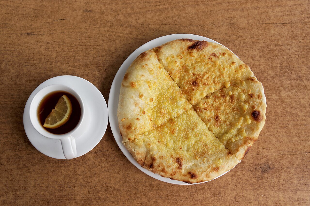 Imeretian khachapuri — Georgian cheese-filled flatbread — served with tea