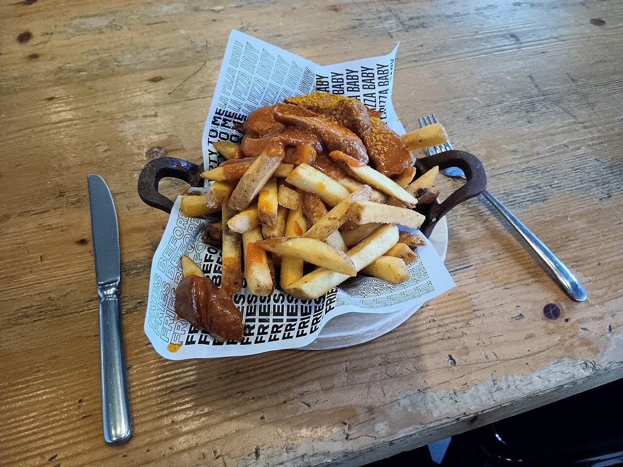 Currywurst dusted with curry powder, served with fries at a restaurant in Berlin