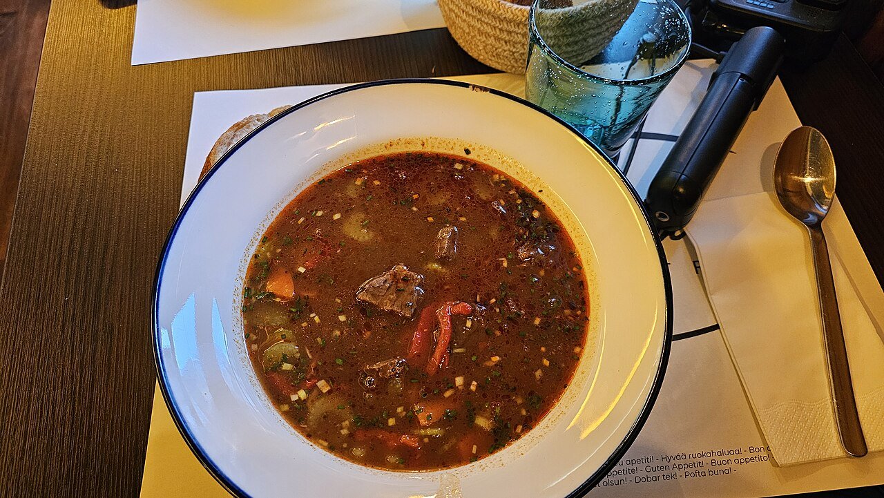 A bowl of Hungarian goulash soup with beef and peppers at a restaurant
