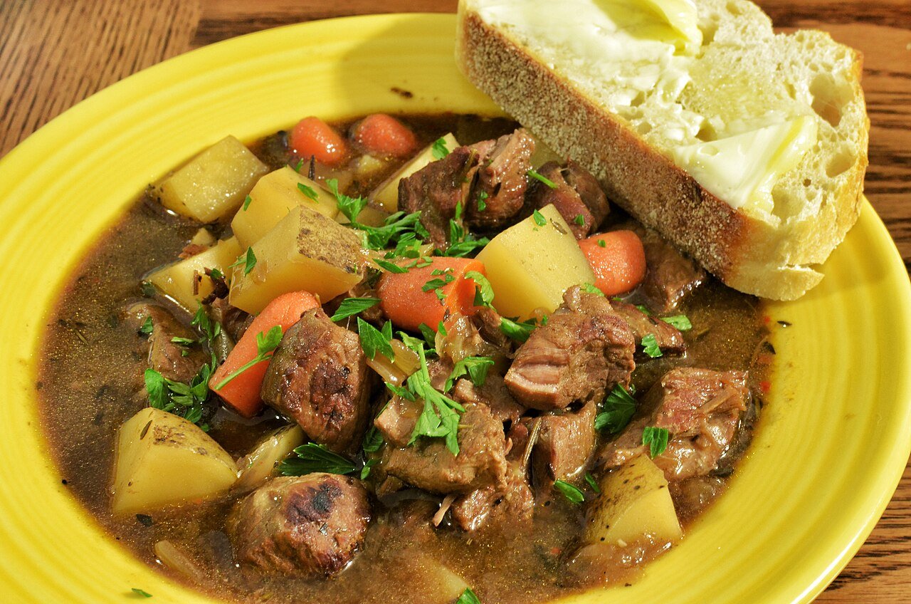 A hearty bowl of Irish stew with beef, potatoes, and carrots, served with buttered bread