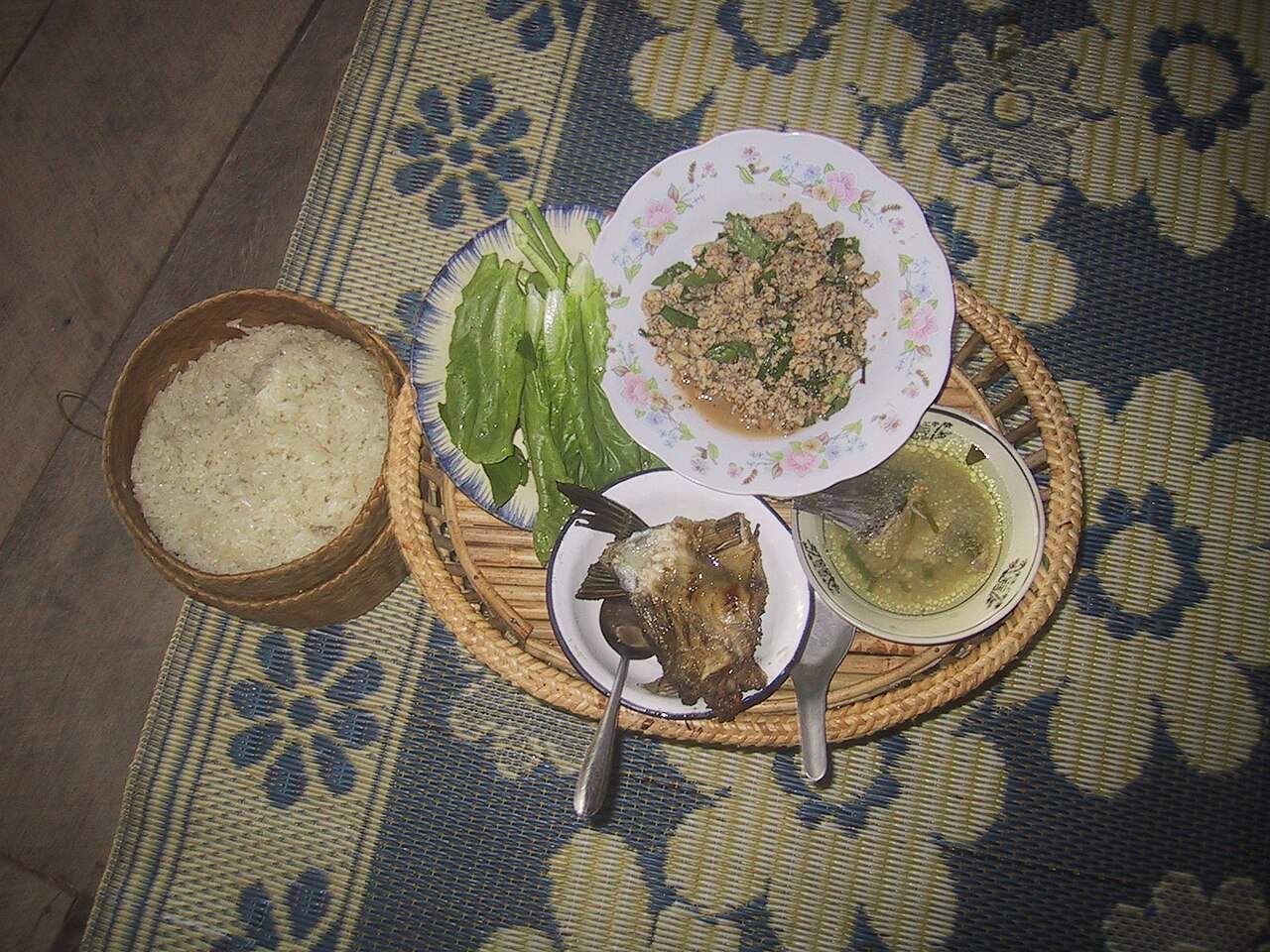 A traditional Lao meal tray with larb fish, grilled fish, soup, salad and sticky rice