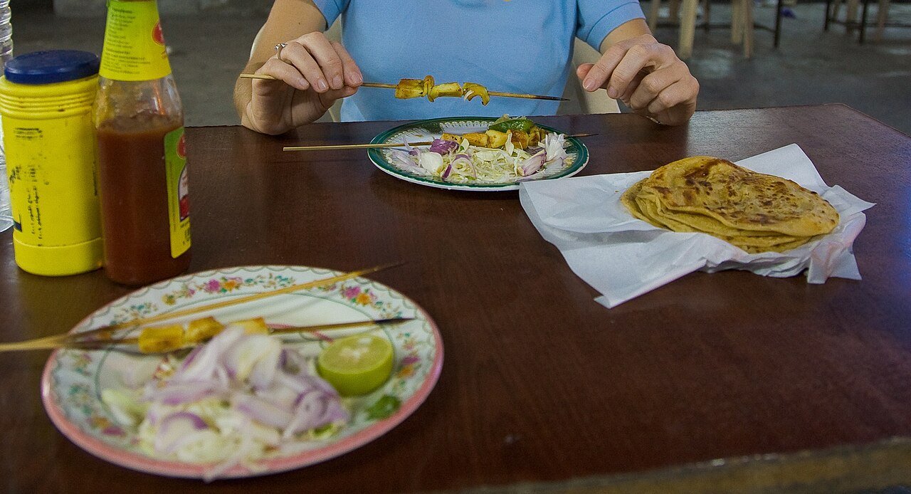 Squid kebab skewers with onions and flatbread at a street-food table in Seeb, Oman