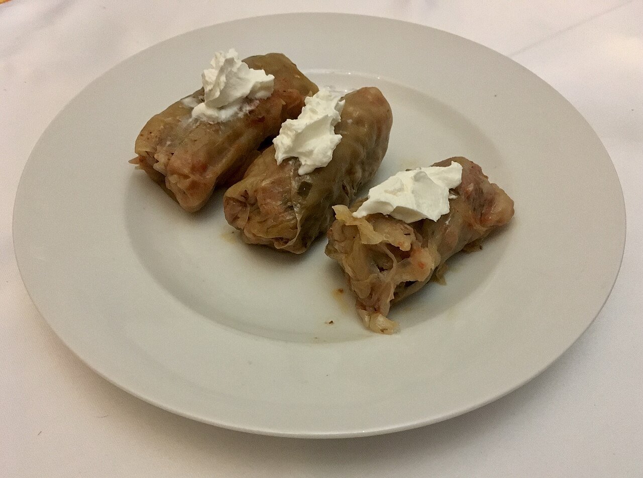 Romanian sarmale — cabbage rolls stuffed with minced meat and rice, topped with sour cream