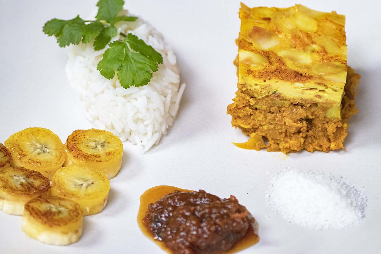 Bobotie — South Africa's spiced minced-meat dish with an egg custard topping — served with rice, fried plantains and chutney