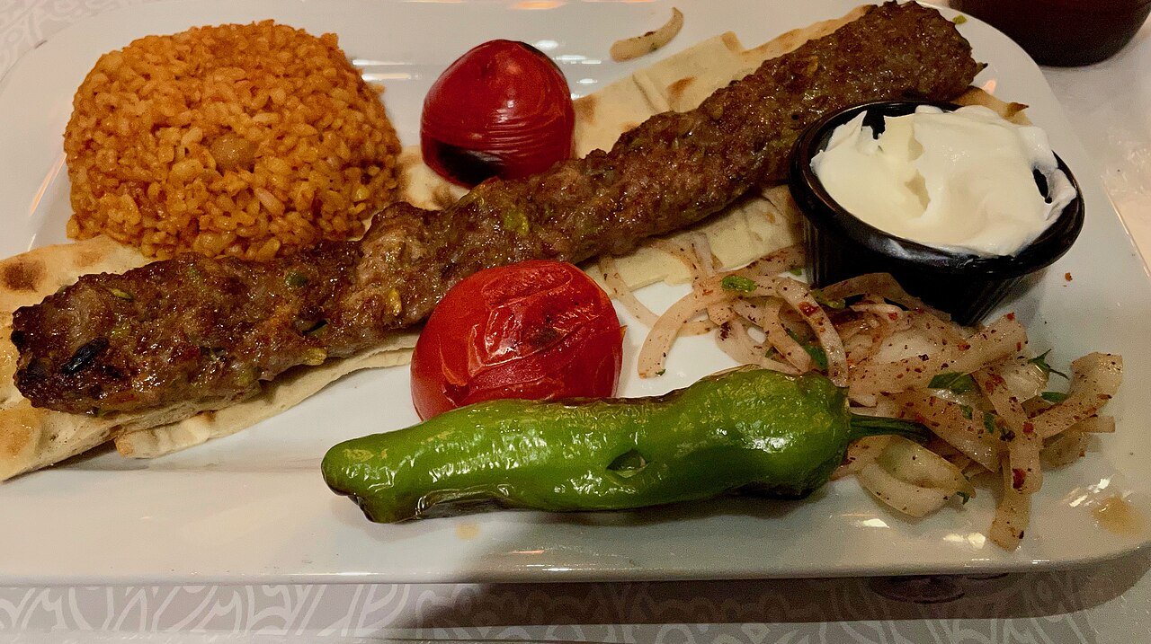A lamb pistachio kebab platter with bulgur, grilled tomatoes, pepper, onions and yogurt in Istanbul, Turkey