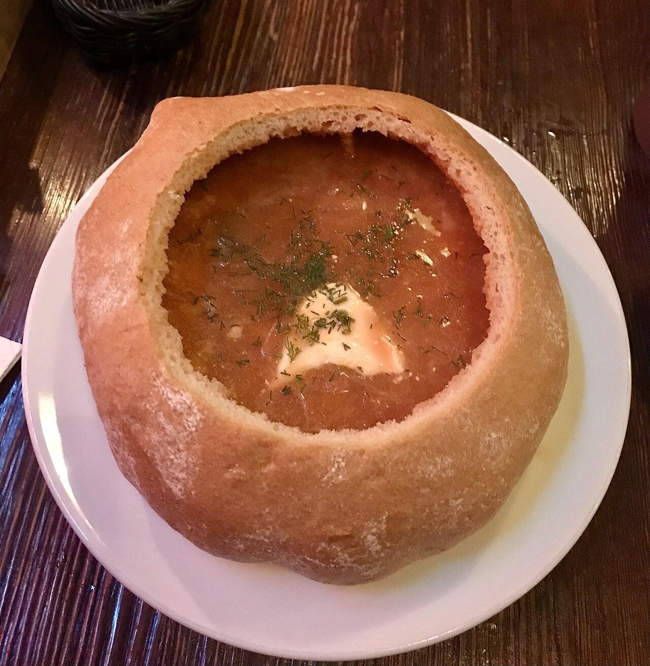 Ukrainian borscht with sour cream and dill served in a hollowed-out bread loaf in Lviv