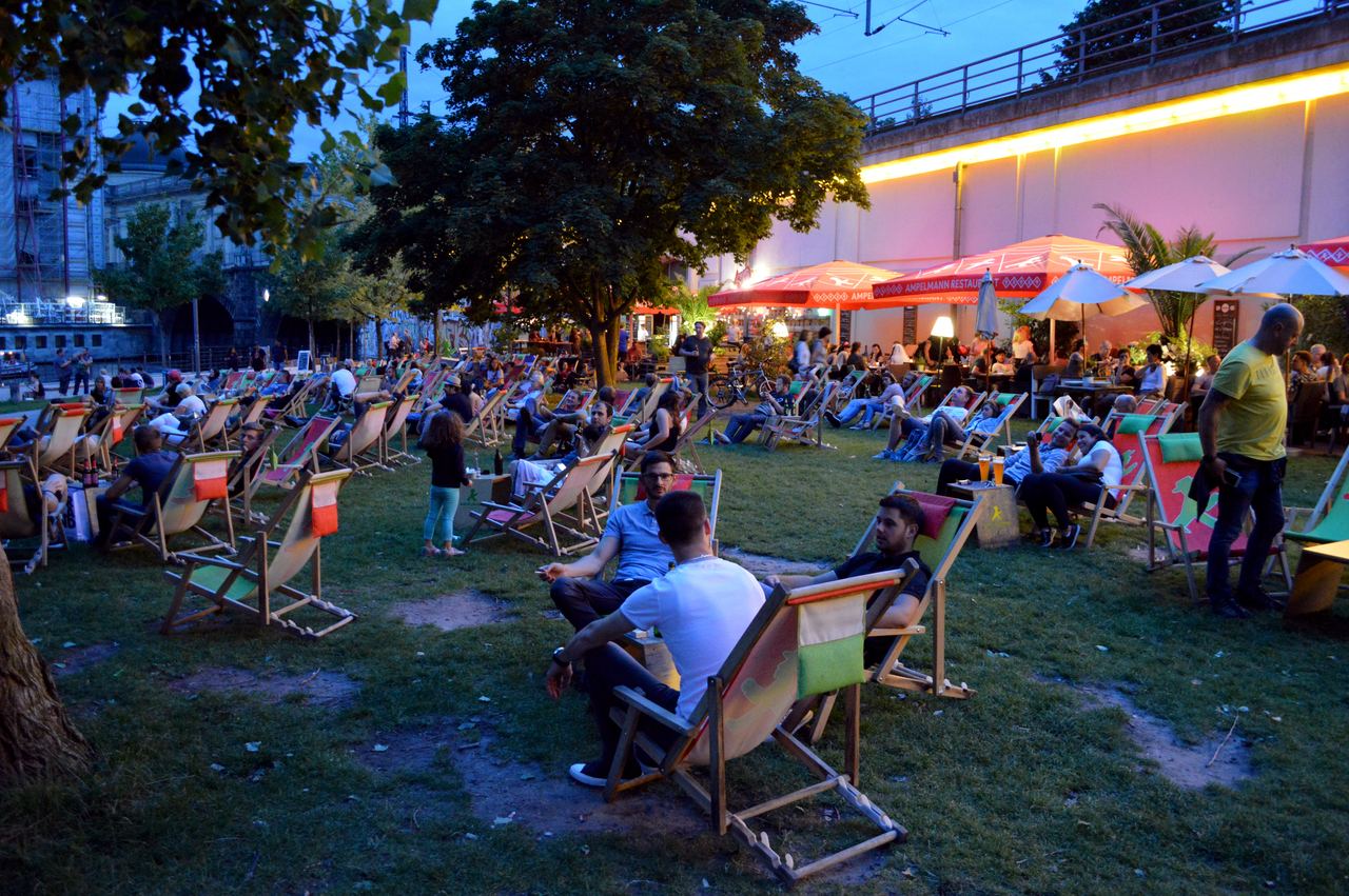 People relax and socialize in James-Simon-Park at dusk in Berlin, Germany