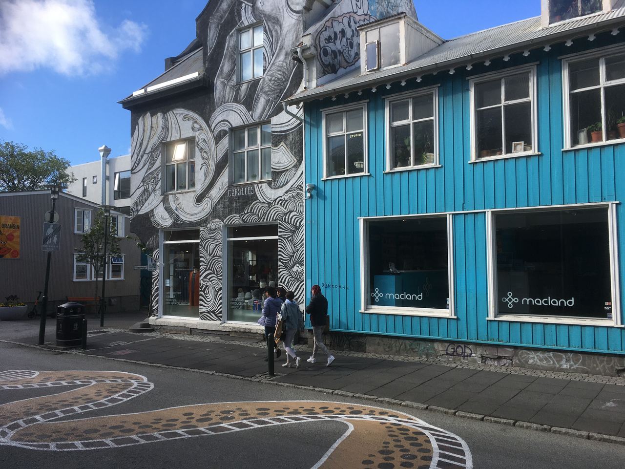 Pedestrians pass colorful corrugated-iron buildings in downtown Reykjavík, Iceland