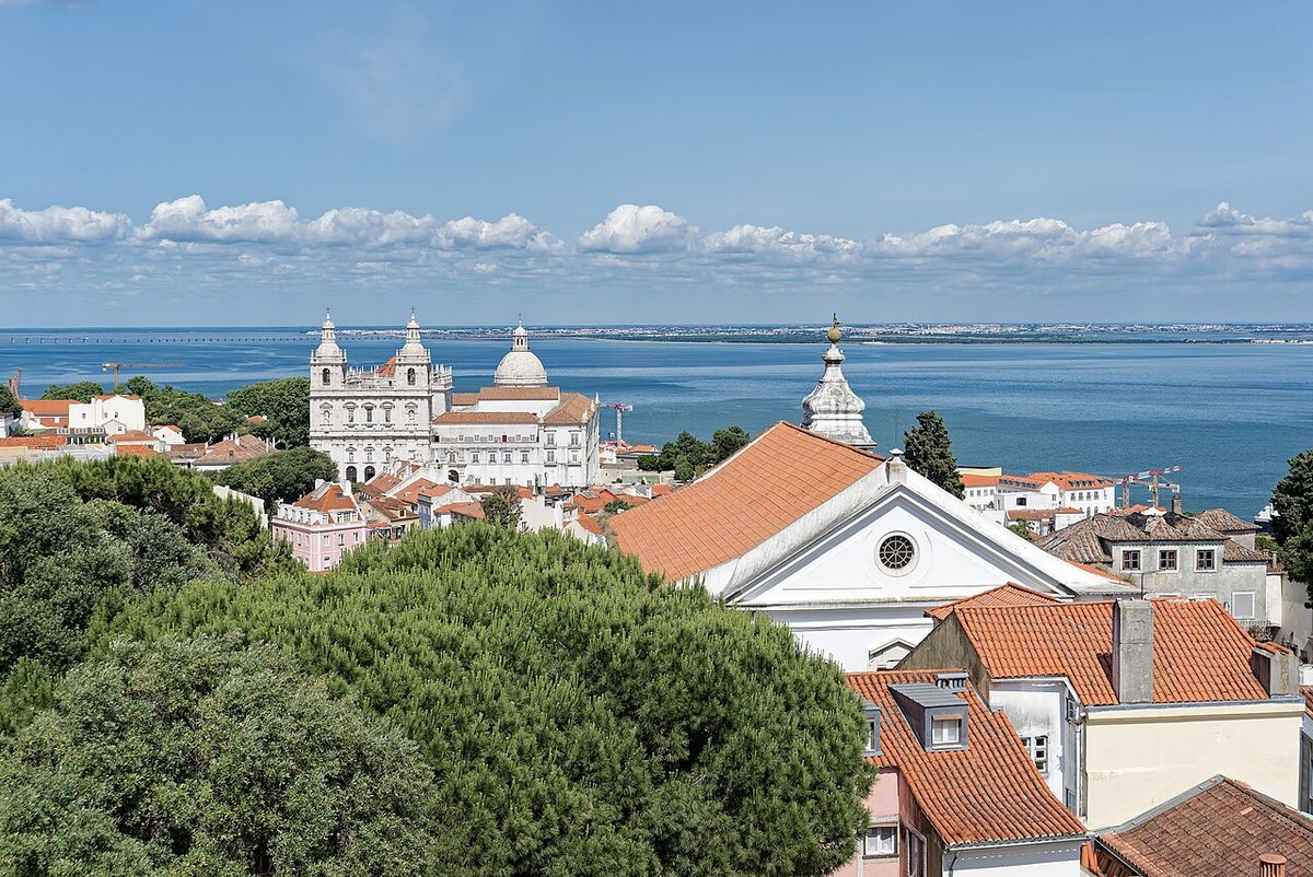 Terracotta rooftops of Alfama, Lisbon, with the Tagus River beyond