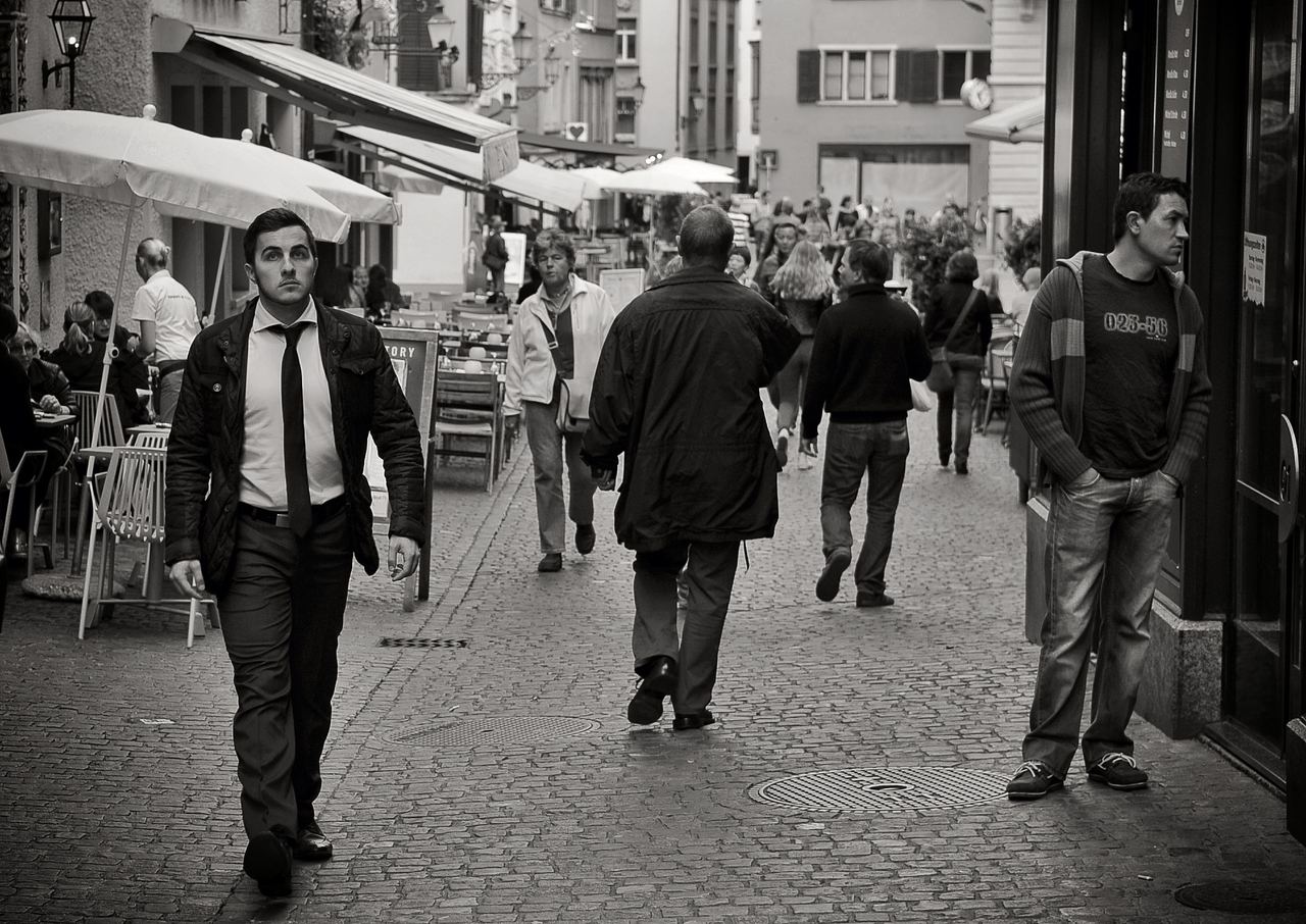 People stroll past cafés on a cobblestone street in Zurich's old town, Switzerland